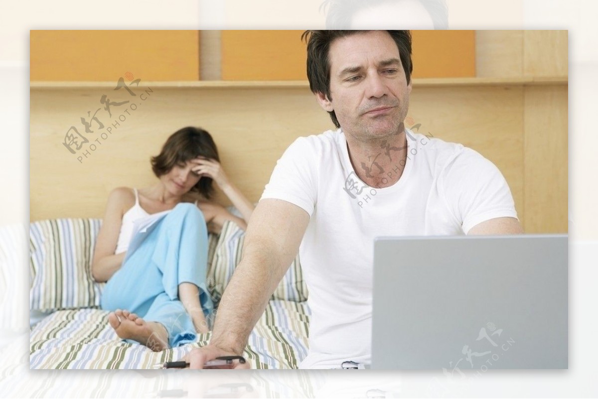 笔记本电脑上工作的丈夫和看书的妻子图片