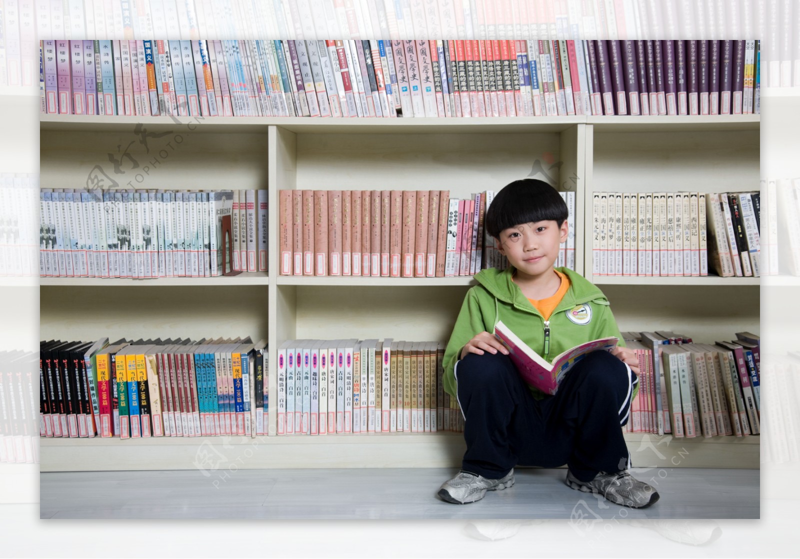 蹲在书架旁的男孩图片图片