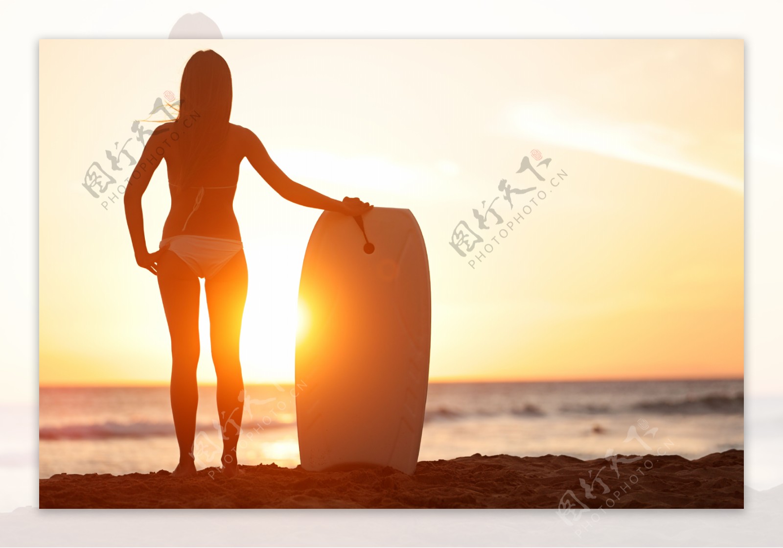 沙滩上拿着冲浪板的美女背影图片
