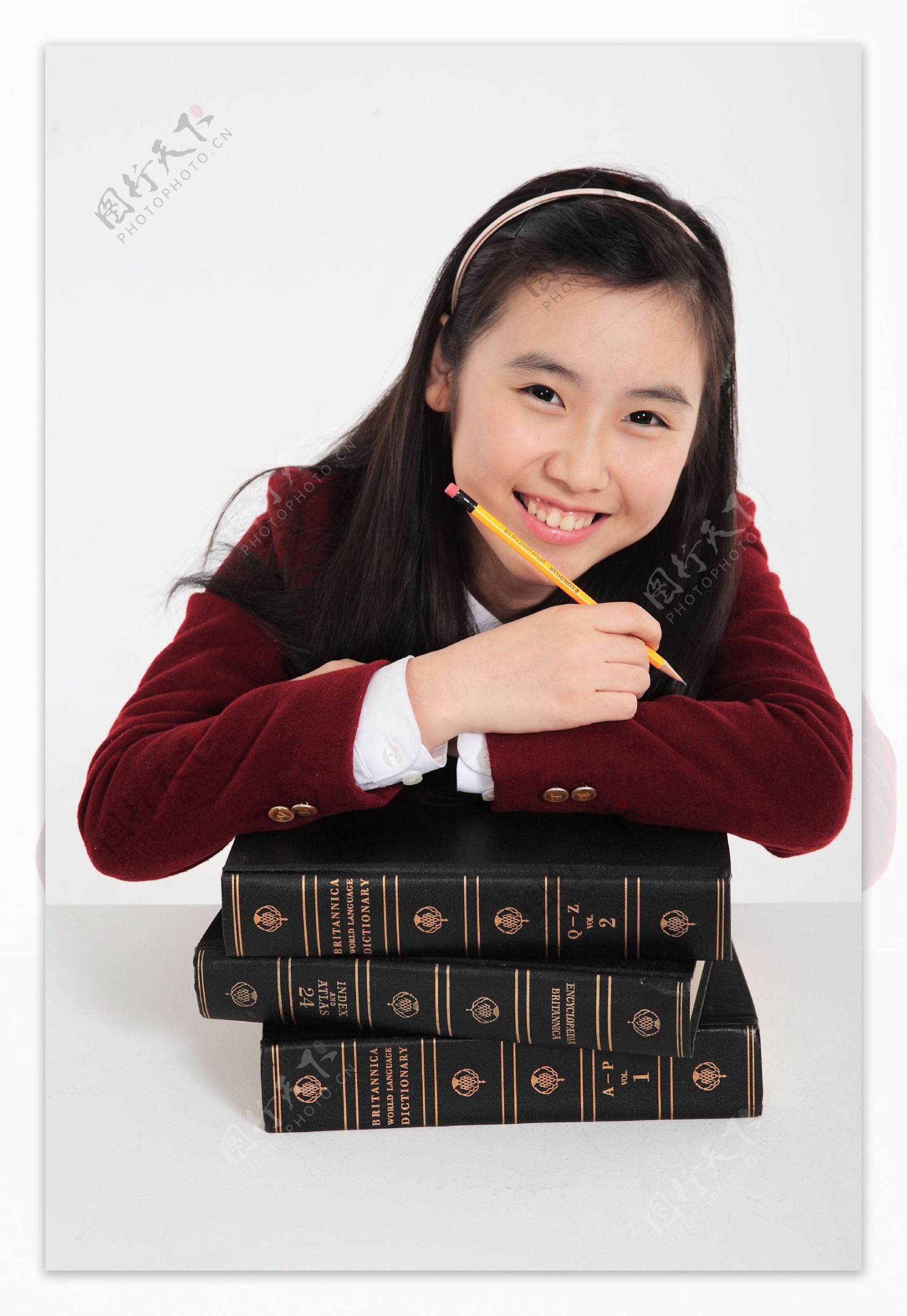 拿着铅笔趴在书本上的开心女生图片
