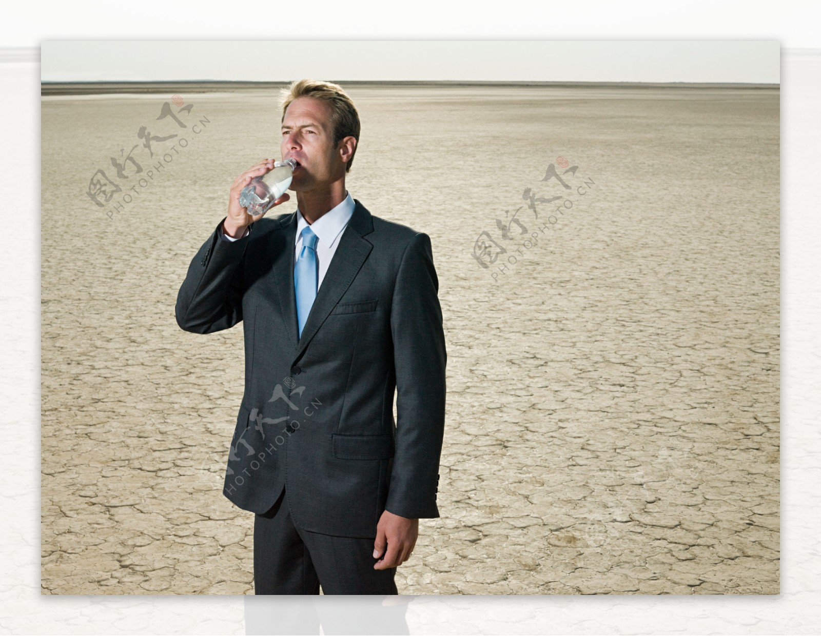 喝着清水在沙漠中凝视前方外国商业男人图片