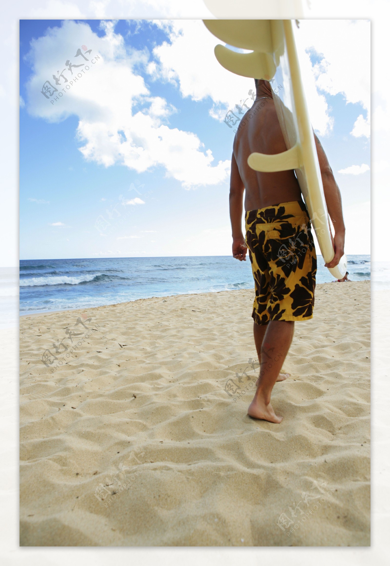 拿着滑板走在沙滩上的男人图片