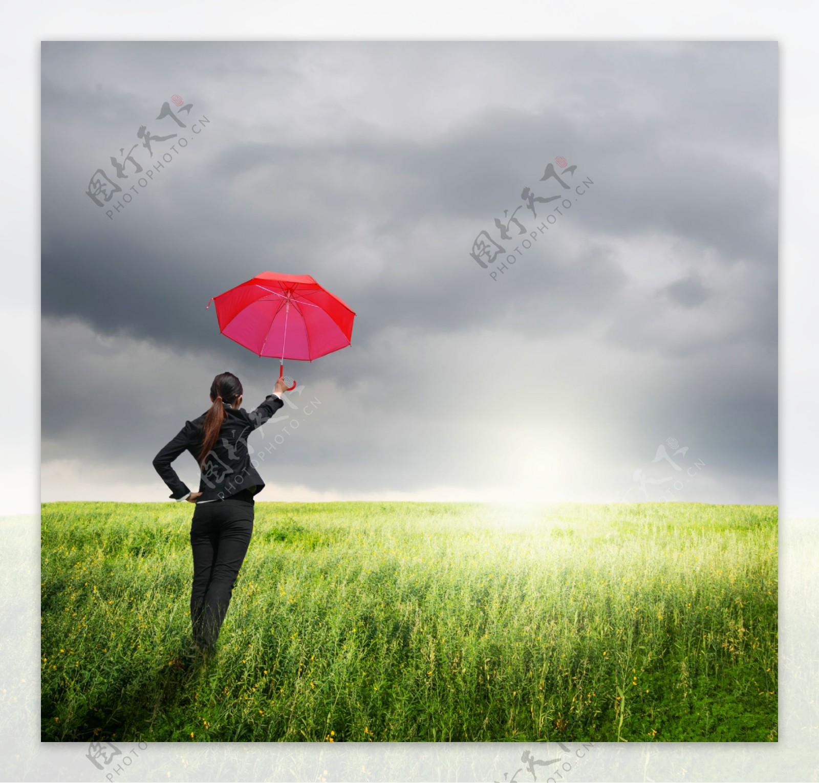 草地上打伞的职业女性图片