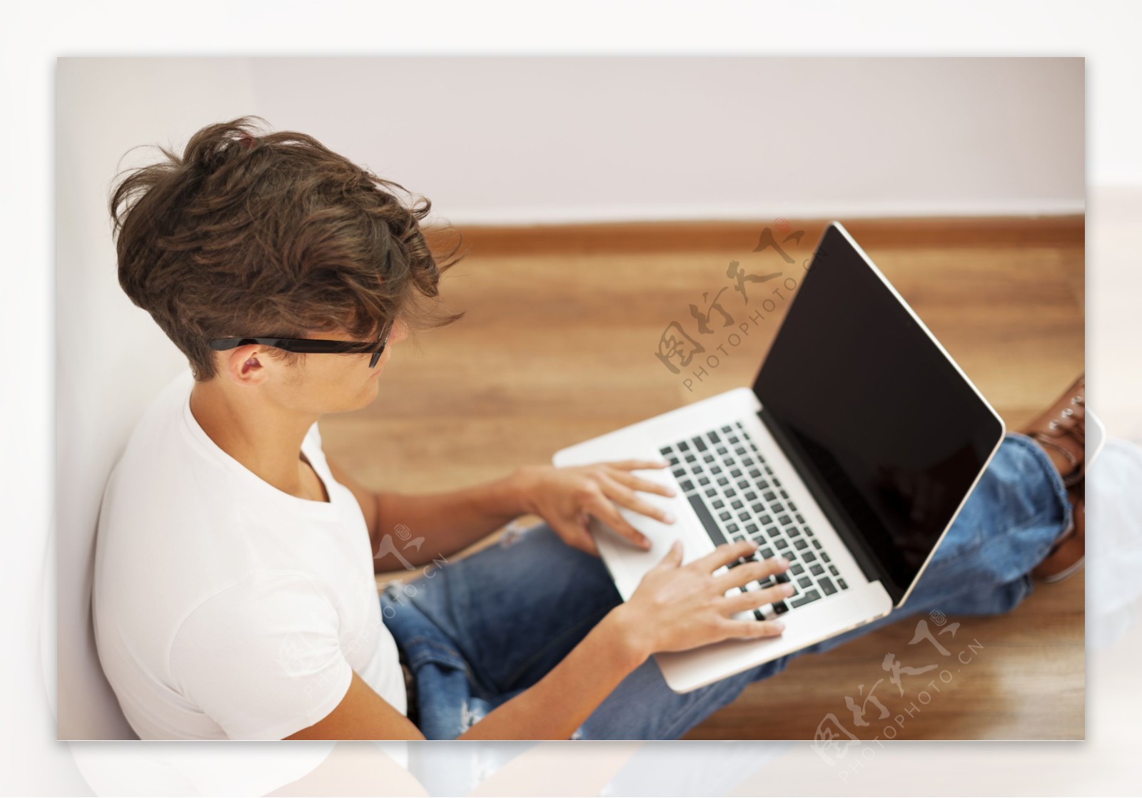 坐在地板上操作电脑的男性图片